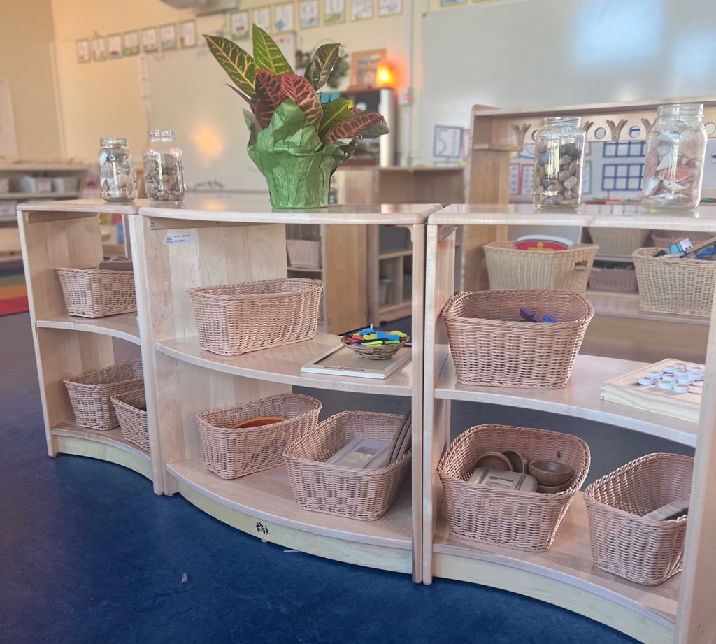 Open wooden shelves with baskets of materials for children